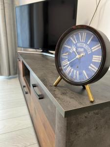 a clock sitting on top of a table with a tv at City Center Sunny Apartment in Suceava