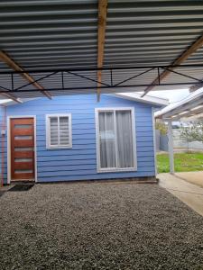 a blue house with a door and a garage at Cabaña in Ancud