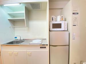 a small kitchen with a refrigerator and a microwave at マルチステイ大阪心斎橋 in Osaka