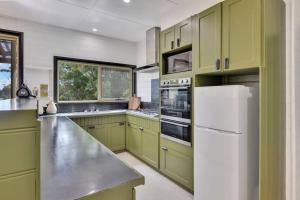 a kitchen with green cabinets and a white refrigerator at Parnella Hideaway in St Helens