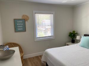 a white bedroom with a bed and a window at Island Time in Carolina Beach