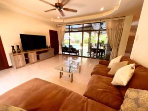 sala de estar con sofá y TV de pantalla plana en Coconut Paradise Holiday Villas, en Rawai Beach