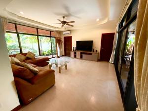 sala de estar con sofá y TV en Coconut Paradise Holiday Villas, en Rawai Beach