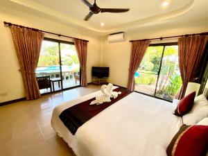 a bedroom with a large white bed and large windows at Coconut Paradise Holiday Villas in Rawai Beach