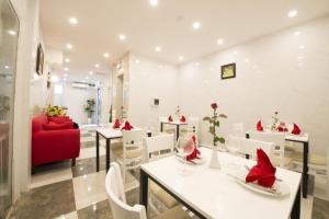 a restaurant with white tables and a red couch at Hanoi Holiday Hotel in Hanoi