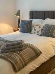 a bed with a blanket and pillows on it at The Burrow, Langholm, Dumfries and Galloway in Langholm