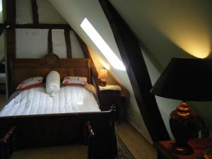 a bedroom with a bed in a attic with a lamp at La Longère Aux Sapins in Fontaine-le-Bourg