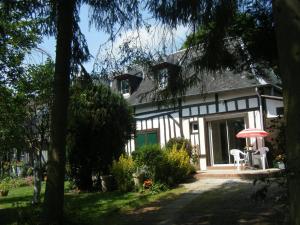 ein weißes und schwarzes Haus mit einem roten Regenschirm in der Unterkunft La Longère Aux Sapins in Fontaine-le-Bourg