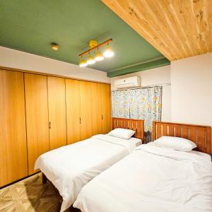 two beds in a room with wood paneling at ueno minowa401 in Tokyo