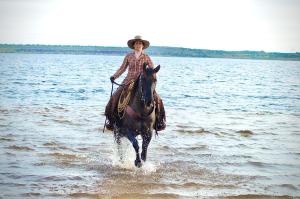 Eine Frau reitet ein Pferd im Wasser in der Unterkunft W Diamonds Ranch in Großräschen