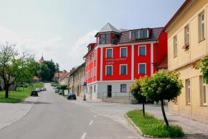 un bâtiment rouge sur le côté d'une rue dans l'établissement Hotel Ostrov Garni, à Sadská