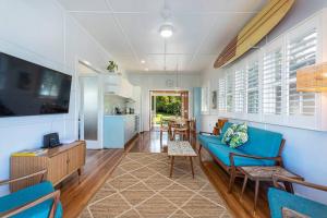 a living room with a blue couch and a kitchen at Stylish 1950s Moffat Beach House in Caloundra