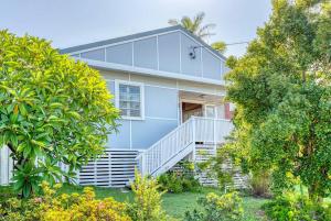 a blue house with stairs and trees at Stylish 1950s Moffat Beach House in Caloundra