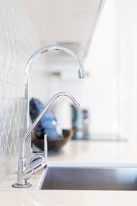 a kitchen sink with a faucet on a counter at Stylish 1950s Moffat Beach House in Caloundra