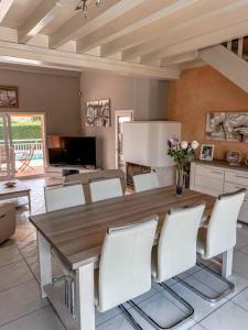 jadalnia z drewnianym stołem i białymi krzesłami w obiekcie Magnifique maison à Lentilly - Piscine w mieście Lentilly
