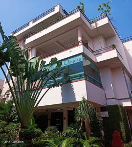 a building with a palm tree in front of it at Hotel The Omaira in Jaipur