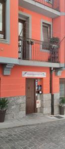 un edificio naranja con puerta y balcón en Andra Mari Apartamentu Turistikoak en Bermeo