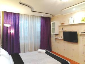 a bedroom with a bed with purple curtains and a tv at 429. Отличный вариант для туриста и командированного in Almaty