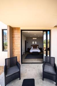 a bedroom with a bed and two chairs at Villa Sophia Valle de Guadalupe in Valle de Guadalupe