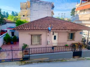 una pequeña casa rosa con una valla negra en lovely place with veranda (Grande), en Larisa