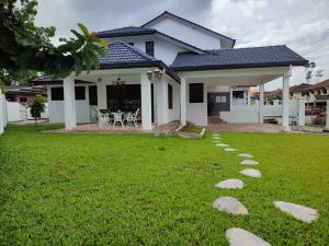 a house with a lawn with rocks in front of it at Casablanca Holiday Home with BBQ Pit in Kuching