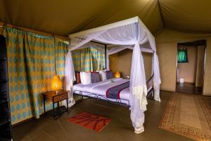 - une chambre avec un lit à baldaquin dans une tente dans l'établissement Ngorongoro Wild Camp, à Ngorongoro