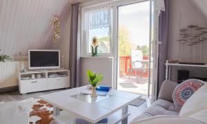 ein Wohnzimmer mit einem weißen Tisch und einem TV in der Unterkunft Sonnenblumenhaus 02 in Prerow