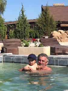 a man and a child in a swimming pool at Pensiunea BELVEDERE YACHTCLUB Berzasca in Berzasca