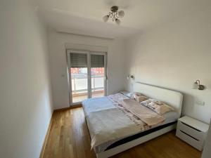 a white bedroom with a bed and a window at Apartment City Life in Podgorica