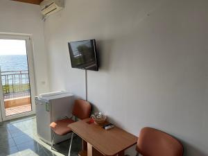 a room with a table and chairs and a tv on the wall at Vila Jolie in Costinesti