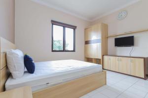 a bedroom with a large bed and a tv at Urbanview Roemah Tebet by RedDoorz in Jakarta