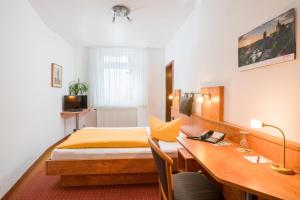 a hotel room with a bed and a desk with a desk at Spree-Pension in Bautzen