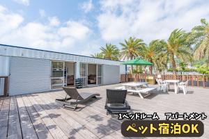 a patio with chairs and tables and a building at DUOマーメイドステイ in Nakagusuku