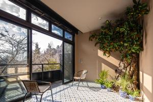 a room with two chairs and a large window at Tateshina Shinyu Onsen in Chino