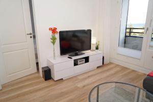 a living room with a flat screen tv on a white cabinet at Ferienwohnung zur Seeseite _ 200 m in Damp