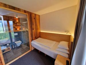 a small bedroom with a bed and a glass window at ENDEMIT Boutique Hotel & Spa in Horní Bečva