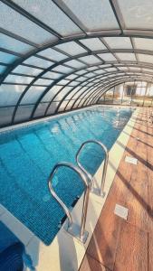 een groot zwembad met een gebogen plafond bij Apartament Baltic Sun in Sztutowo