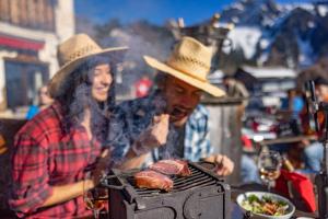 a man and woman in cowboy hats cooking food on a grill at Le Coucou Hotel Restaurant & Lounge-Bar in Montreux