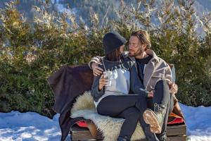 a man and woman sitting on a bench in the snow at Le Coucou Hotel Restaurant & Lounge-Bar in Montreux