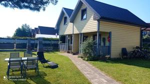 a house with a table and chairs in the yard at Apartament Teo -Rewal in Rewal