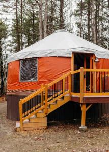 an orange yurt with a porch and stairs in the woods at Heated & AC Yurt in Penn Yan