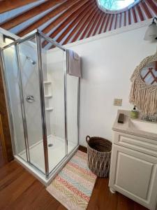 a bathroom with a glass shower and a sink at Heated & AC Yurt in Penn Yan