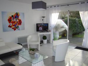 ein Wohnzimmer mit 2 weißen Stühlen und einem TV in der Unterkunft Maison Cucq-Stella Plage, 4 pièces, 6 personnes - FR-1-236-108 in Cucq