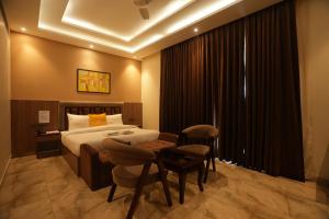 une chambre d'hôtel avec un lit, une table et des chaises dans l'établissement Lime Tree Hotel and Banquet Greater Noida, à Greater Noida