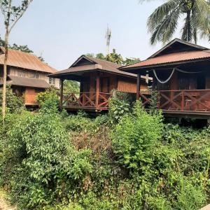 ein Haus auf einem Hügel mit Bäumen und Sträuchern in der Unterkunft Maylyn Guesthouse in Vang Vieng