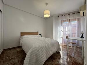 Dormitorio blanco con cama y mesa en Experiencia Centro Cartagena, en Cartagena