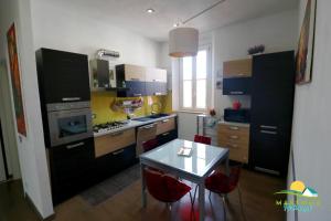 kuchnia ze stołem i czerwonymi krzesłami w obiekcie Maremma Holidays -Trento Apartment w mieście Follonica