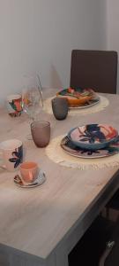 a wooden table with plates and cups and a wine glass at CASA PRIMAVERA in Vado Ligure