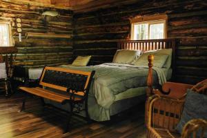 ein Schlafzimmer mit einem Bett und einer Bank in einem Blockhaus in der Unterkunft Rustic Ridge in Penn Yan
