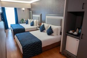 duas camas num quarto de hotel com almofadas azuis e brancas em Nova Plaza Park Hotel em Istambul
